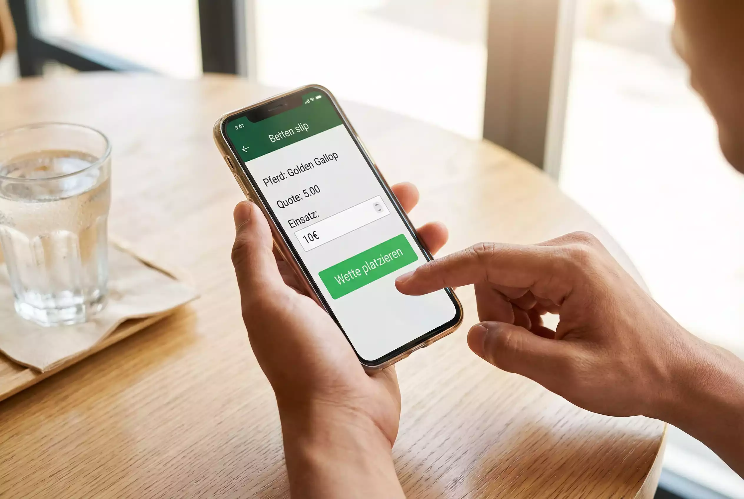 Erste Pferdewette platzieren – Person tippt auf Smartphone-Bildschirm mit Wettschein